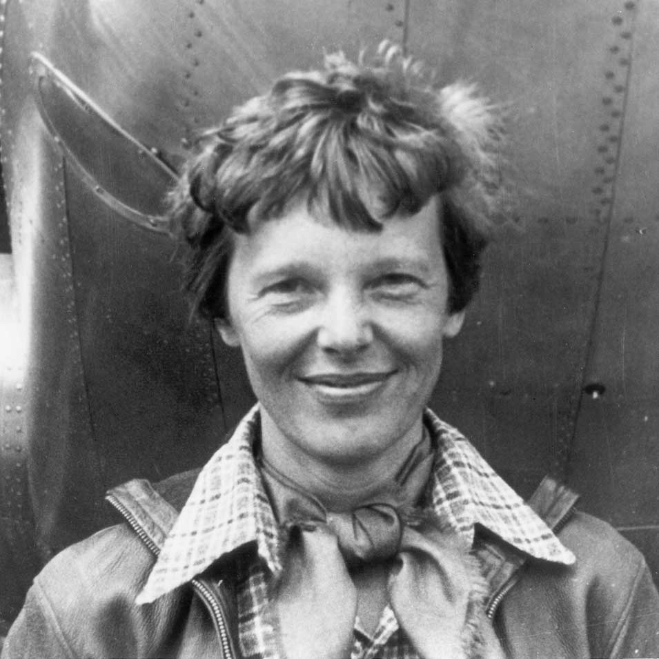 Amelia Earhart standing under the nose of her Lockheed Model 10-E Electra. 